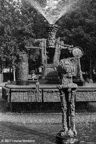 Assis derrière une sculpture fontaine